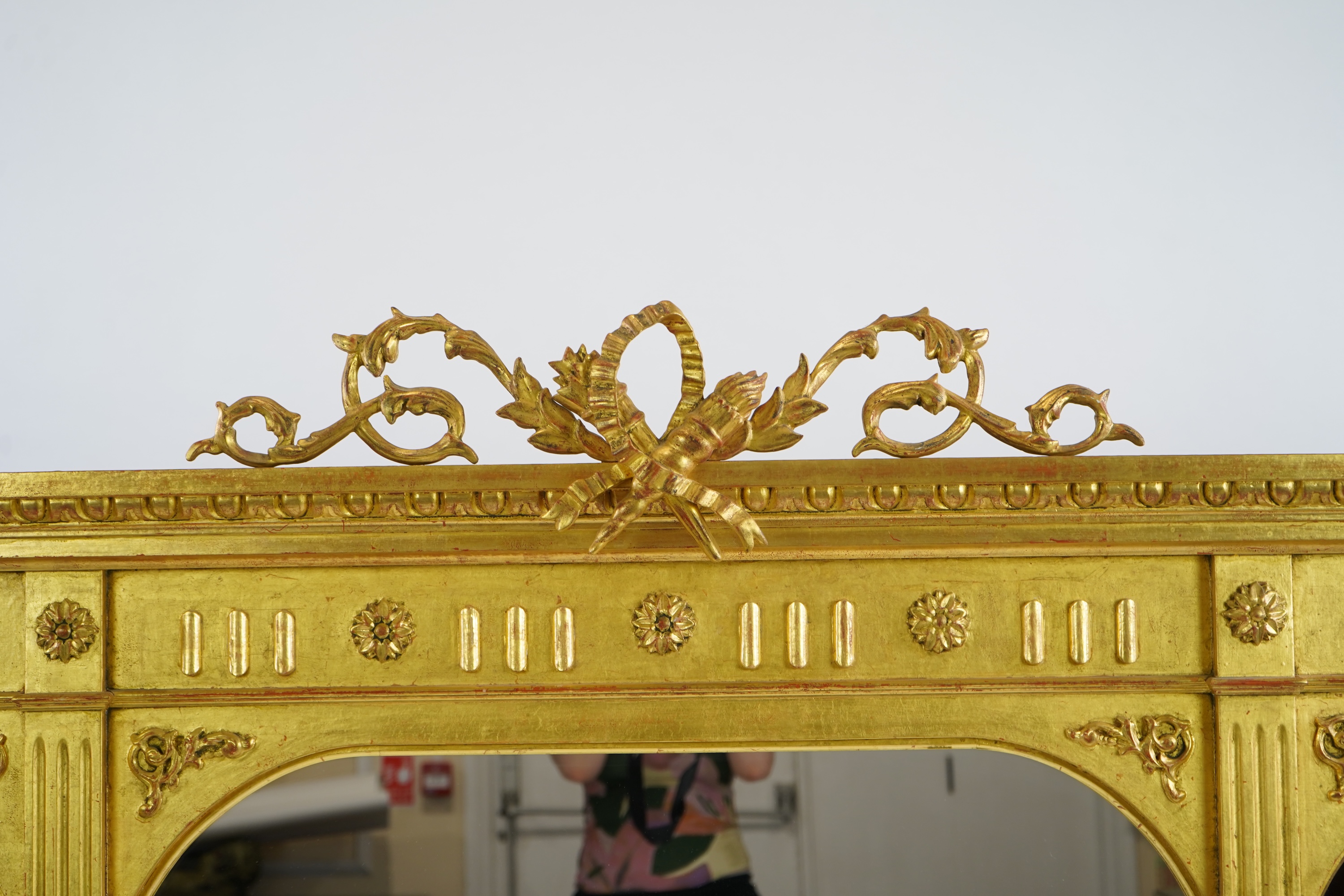 A Victorian style giltwood and composition triple plate overmantel mirror, with foliage scroll torch pediment over a flower head frieze and fluted pillars, 222cm wide,152cm high